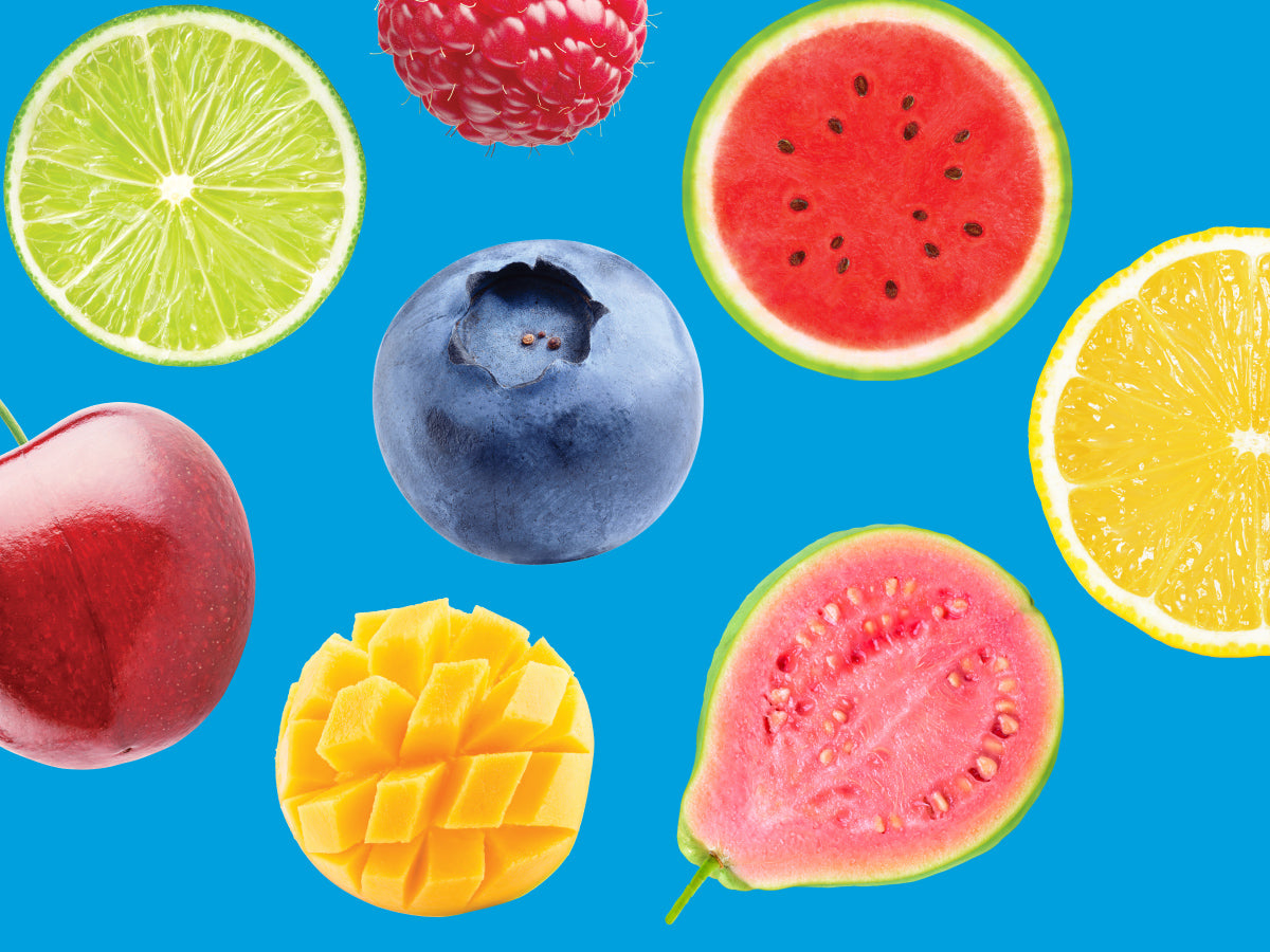 Assorted fruits including a lime, raspberry, watermelon, blueberry, cherry, mango, and guava on a blue background.