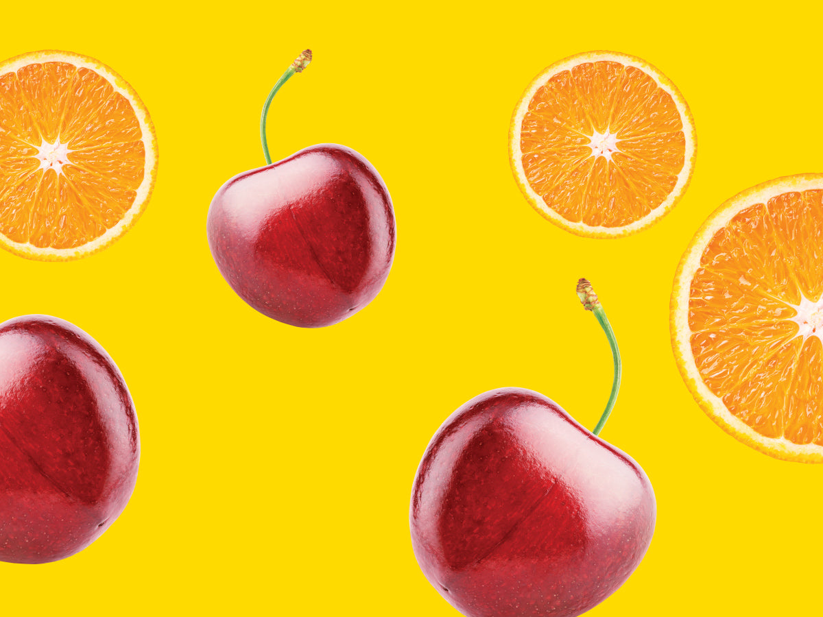 Red cherries and orange slices on a yellow background