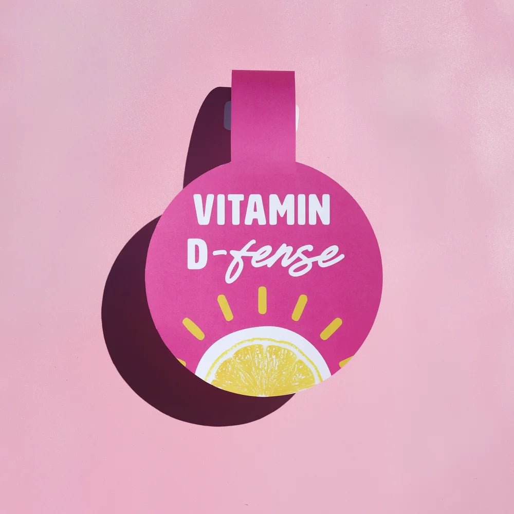Vitamin D supplement bottle with lemon slice on a pink background